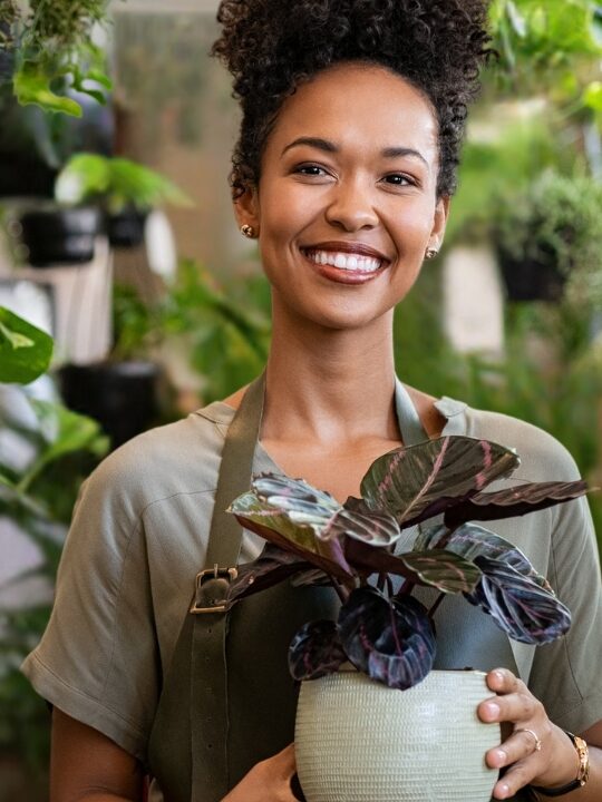 woman of color business owner holding a plant in her floral shop