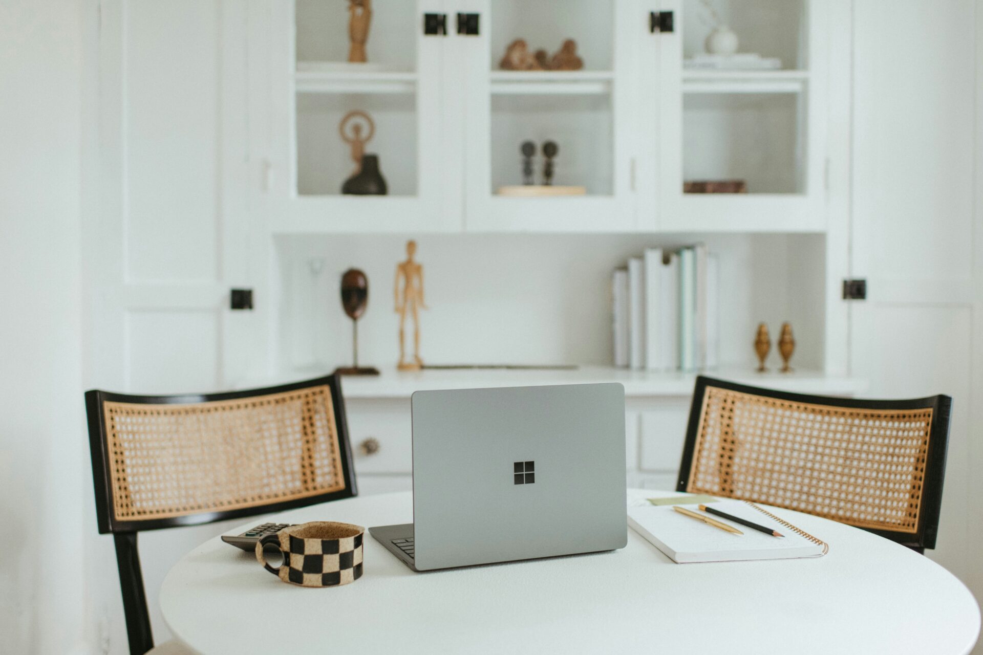 Two wicker office chairs around a table with a laptop on top